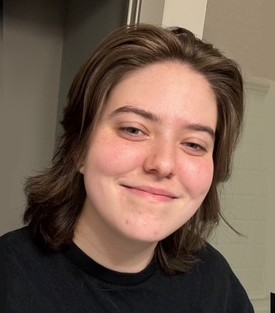 Samantha Osborne facing the camera with a black shirt on and a middle wolfcut hair style